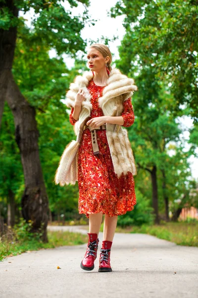 Russian beauty woman. Full body portrait of a stylish model in long red flowers dress and fur vest