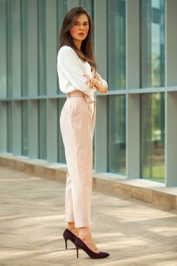 Tam boy portre, beyaz bluz ve ofiste pembe pantolon giyen güzel esmer kadın.