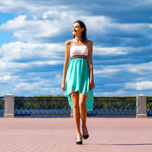 全长肖像画穿着青绿色衣服的年轻漂亮的姑娘沿着堤岸散步 — 图库照片