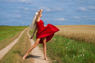 Kırmızı elbiseli güzel sarışın bir kadının vücut portresi.