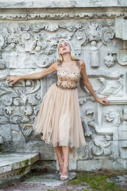 Bej elbiseli güzel sarışın bir kadının vücut portresi.