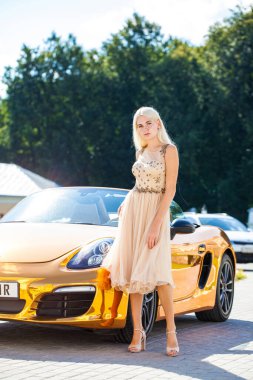 Açık hava parkında bej elbiseli güzel bir sarışının vücut portresi.