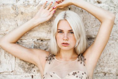 Bej elbiseli güzel sarışın bir kadının portresi.