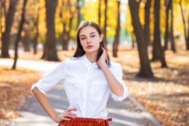 Güz parkında genç ve güzel bir esmer kadının portresi.