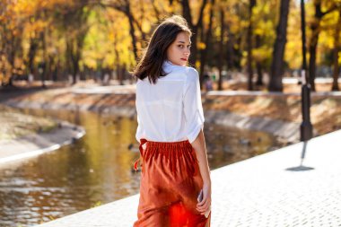 Güz parkında genç ve güzel bir esmer kadının portresi.