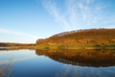 Yatay, göl yansıma ve mavi gökyüzü bulutlu karşı orman ile akşam
