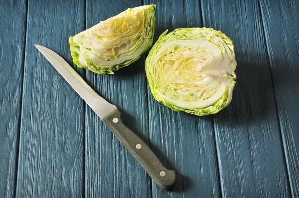 Bıçak mavi ahşap arka plan üzerinde beyaz lahana dilimlerle