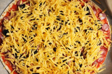 Yakın çekim, dilimlenmiş siyah zeytin, sosis, peynir pizza hamuru masada ketçap sosu ile