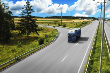 Mavi kamyon römork hareket alanları ve mavi gökyüzü bulutlu yeşil ağaçları ile de kırsal yol ile