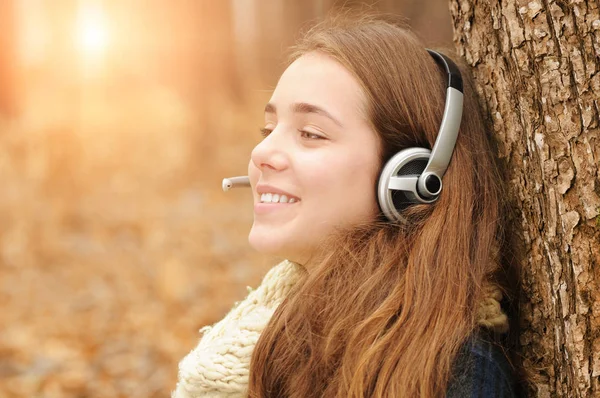 Giovane Ragazza Con Auricolare Sorridente Nel Parco Autunnale Con Foglie — Foto Stock