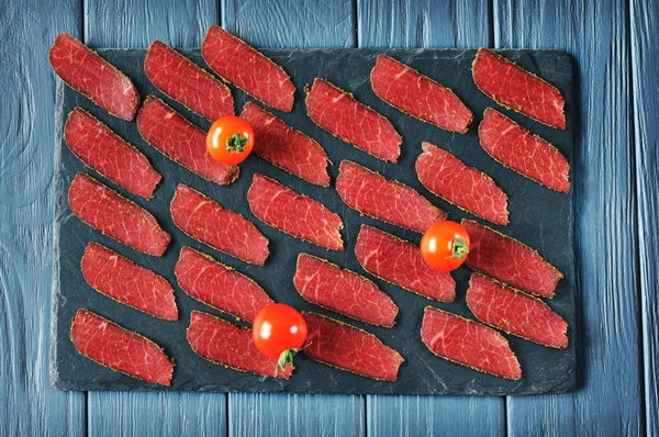 Fette Carne Affumicata Rossa Con Spezie Pomodori Maturi Tavola Scura — Foto Stock