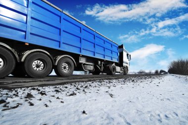 Beyaz kamyon ve kar mavi gökyüzü bulutlu karşı olan kış kırsal yol üzerinde metin için yer ile mavi römork