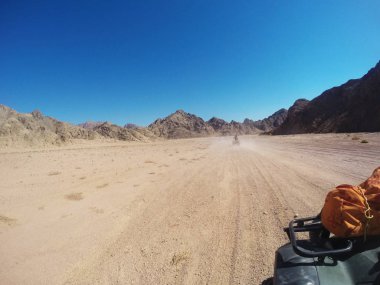 Mavi gökyüzü karşı dağlar ile Quad bisiklet kum çöl