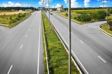 Arabalar ve orman alanları ile beyaz bulutlar mavi gökyüzü ile olan kırsal yol