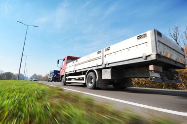 Flatbed kamyon ve otomobil hareket gökyüzü karşı kırsal yolda