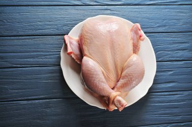 Koyu mavi ahşap arka plan üzerinde beyaz seramik plaka üzerinde çiğ tavuk