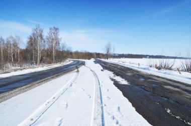 Boş kırsal yol ve kışın kar ve mavi gökyüzü ile orman
