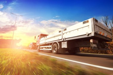 Flatbed kamyon ve otomobil hareket gökyüzü günbatımı ile kırsal yolda
