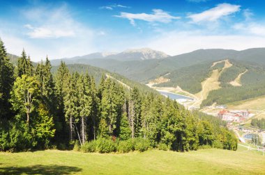 Yeşil orman, ski resort binalar ve mavi gökyüzü bulutlu yaz aylarında Karpat Dağları