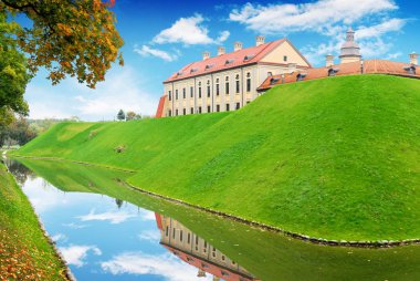 Mavi gökyüzü bulutlu karşı eski kale binalar ile sonbahar orman ve yeşil tepeye gölet