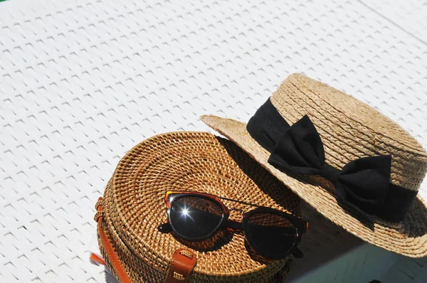 Round straw bag and straw hat with black sunglasses on white background
