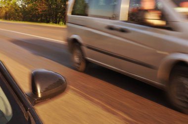 Blcak araba yan ayna ve diğer araba akşam yeşil ağaçlar ile hareket kırsal yolda hızlı sürüş