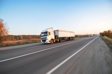 Hareket ve beyaz römork ve açık gökyüzüne karşı kırsal yolda araba büyük kamyonlar