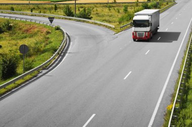 Kırsal yolu üzerinde gri römork ile beyaz ve kırmızı kamyon