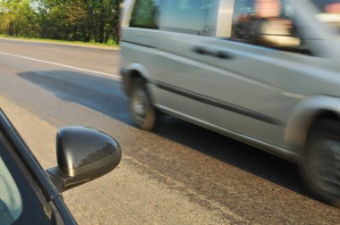 Blcak araba yan ayna ve yeşil ağaçlar ile hareket kırsal yolda hızlı sürüş diğer araba