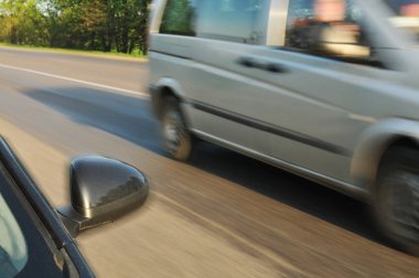 Siyah araba yan ayna ve yeşil ağaçlar ile hareket kırsal yolda hızlı sürüş diğer araba