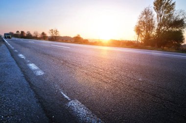 Parlak gün batımı ile berrak gökyüzüne karşı kamyon ve araba ile hareket asfalt kırsal yol