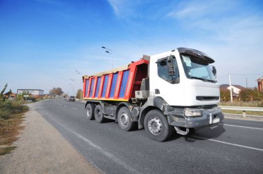 Büyük beyaz çöp kamyonu mavi gökyüzüne karşı kırsal yolda