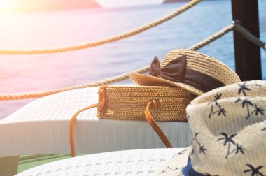 Plastik şezlonglarda saman çuvalları ve hasır şapkalar iskelede şezlonglar ve arka planda güneş ışığı olan deniz.