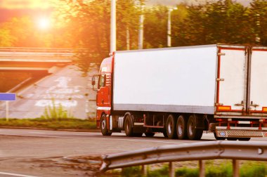 Kırsal yolda gün batımında gökyüzüne karşı yazı için yeri olan beyaz karavanlı kırmızı bir kamyon.