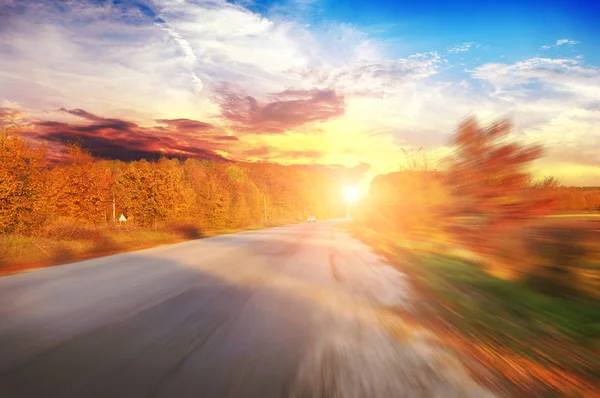 車で移動中の田舎道と日没と青空に対する茂みと秋の森 — ストック写真