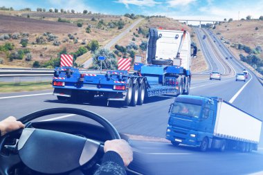 Karavanı yolda olan kamyonlarla soyut bir arkaplan, mavi bulutlu gökyüzüne karşı kamyon direksiyonu