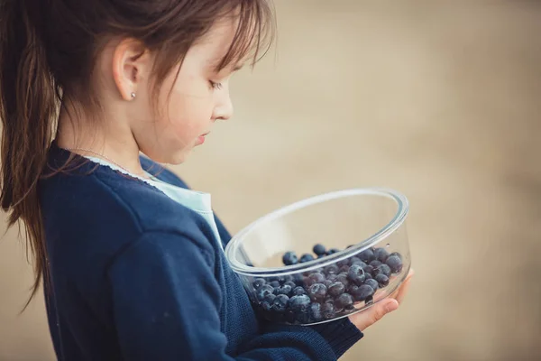 Het eten van bosbessen uit een glazen kom meisje — Stockfoto