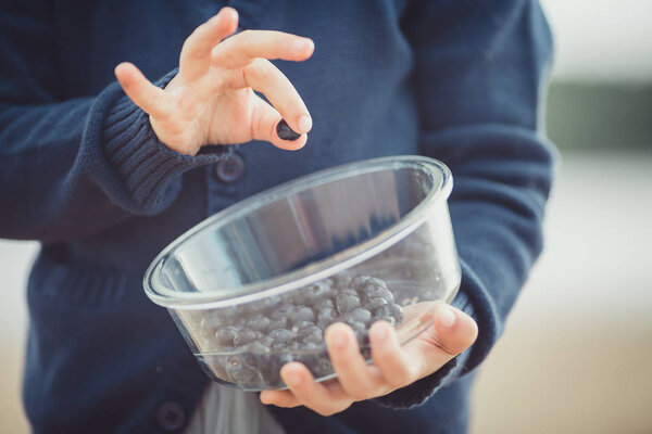 The girl eating blueberries from a glass bowl 