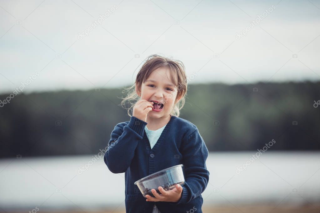 The girl eating blueberries from a glass bowl 