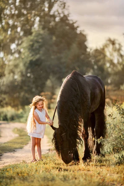 Bambina con stallone friesiano nero — Foto Stock