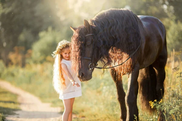 Little  girl with black friesian stallion — Stock Photo, Image