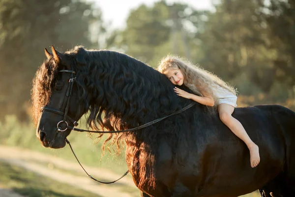 Menina com garanhão friesiano preto — Fotografia de Stock