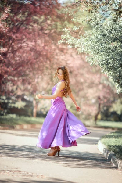 Hermosa mujer joven en un parque de flores — Foto de Stock