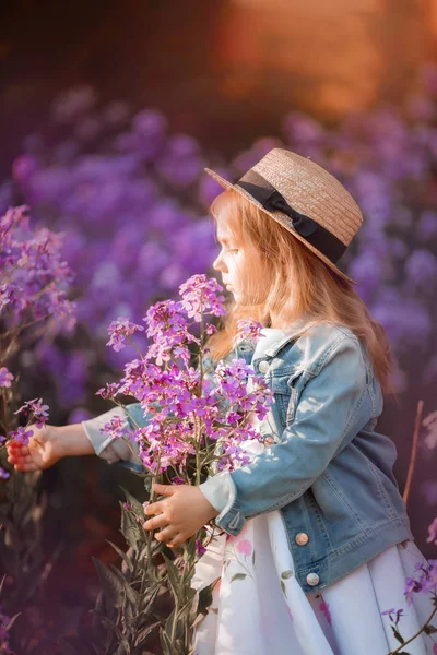 Klein meisje buiten portret in een roze bloemen — Stockfoto