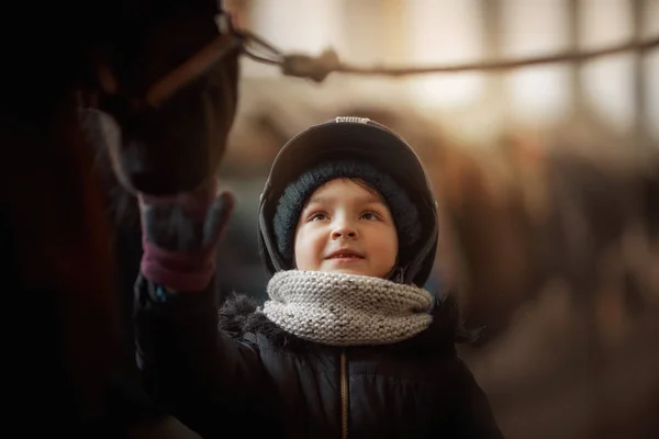 Tiener meisje staande met paard in een stal — Stockfoto