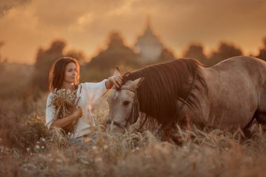 Günbatımında tarlada İspanyol gümüşü ata binen güzel genç bir kadın.