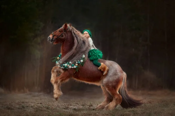 Yeşil Elbiseli Küçük Kız Noel Çelenginde Kırmızı Teneke Atın Üstünde — Stok fotoğraf