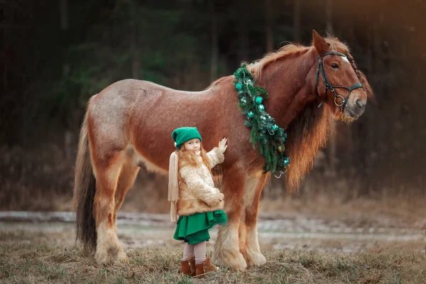 Yeşil Elbiseli Küçük Kız Noel Çelenginde Kırmızı Teneke Atın Üstünde — Stok fotoğraf