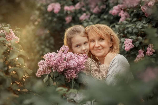 Sorridente Bambina Abbraccia Con Nonna Giardino Lilla Primaverile — Foto Stock