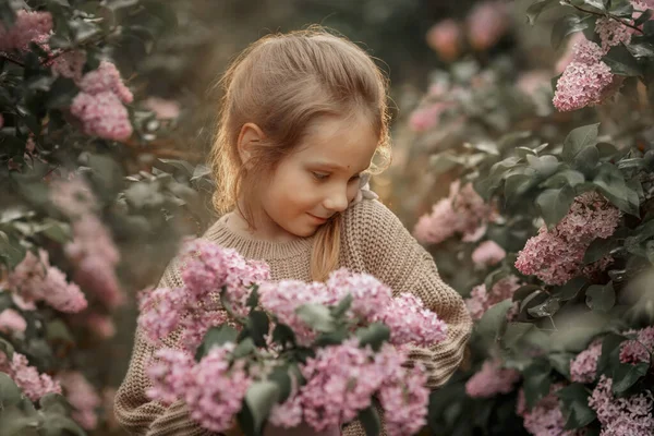 在春天的花园里微笑着的小女孩 戴着一束紫丁香花 — 图库照片